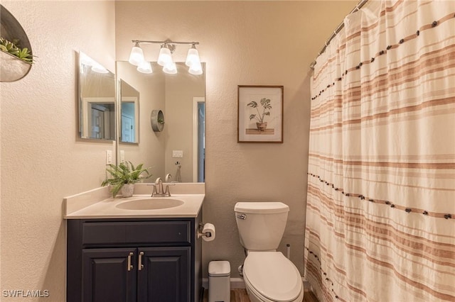 full bath with vanity, toilet, a textured wall, and curtained shower