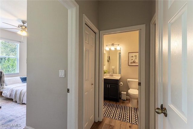 bathroom with toilet, a ceiling fan, wood finished floors, vanity, and connected bathroom