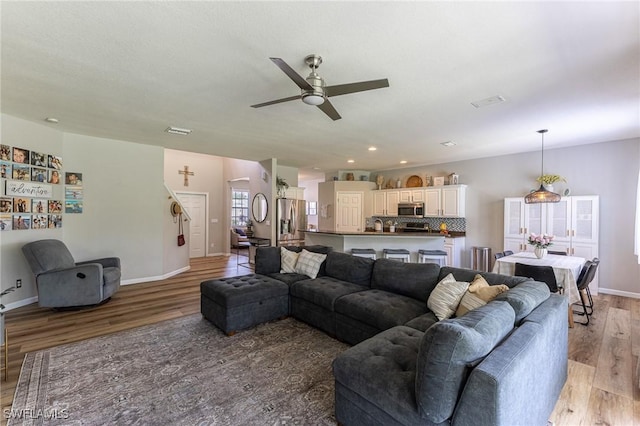 living room featuring light wood-type flooring, ceiling fan, baseboards, and recessed lighting