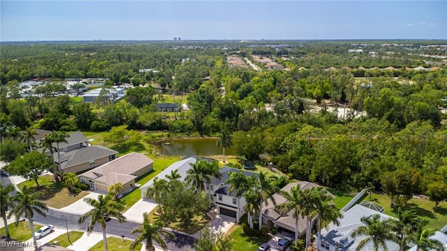 aerial view of property and surrounding area featuring a heavily wooded area, a large body of water, and nearby suburban area