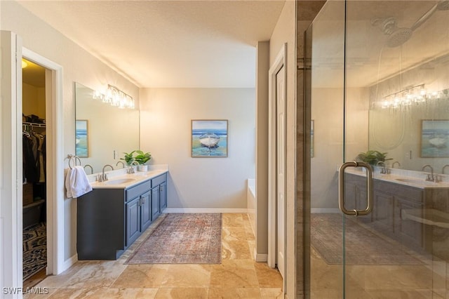 full bathroom with a stall shower, double vanity, a garden tub, a walk in closet, and baseboards