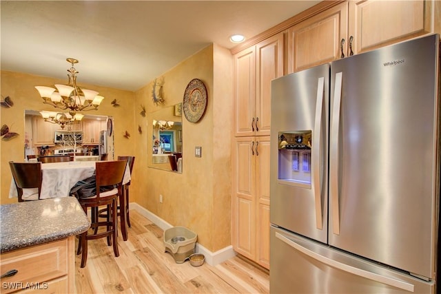 kitchen with light wood-style flooring, a chandelier, appliances with stainless steel finishes, hanging light fixtures, and baseboards