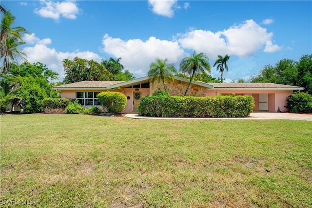 ranch-style home with a front yard, a tiled roof, driveway, and stucco siding
