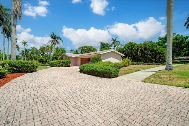 view of front of property with a garage, stucco siding, decorative driveway, and a front lawn