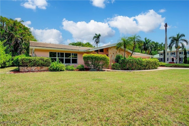 ranch-style home featuring a front yard, stucco siding, and a tile roof