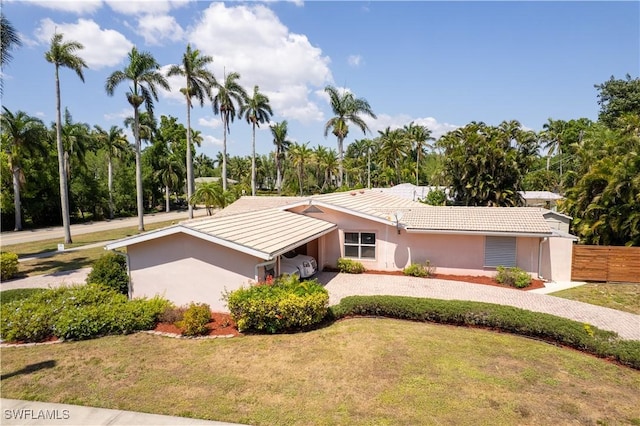 mid-century modern home with a front lawn, fence, stucco siding, and gravel driveway