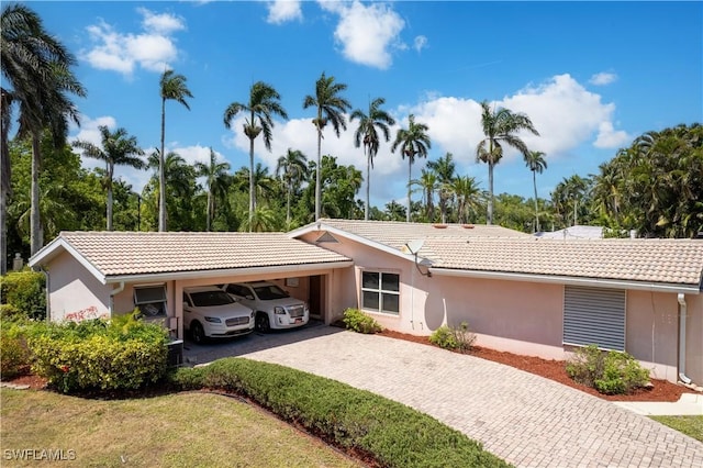 ranch-style house featuring a tile roof, driveway, and stucco siding