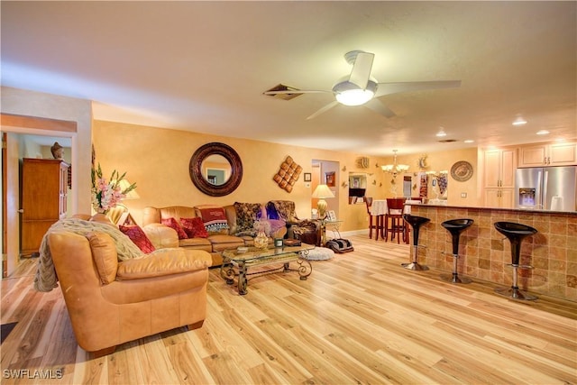 living area featuring baseboards, recessed lighting, light wood-style flooring, visible vents, and ceiling fan with notable chandelier