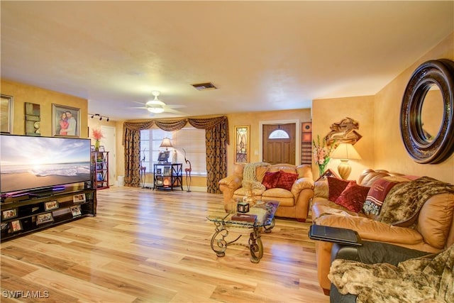 living area featuring visible vents, ceiling fan, wood finished floors, and baseboards