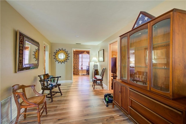 hall featuring light wood-style floors, baseboards, and visible vents