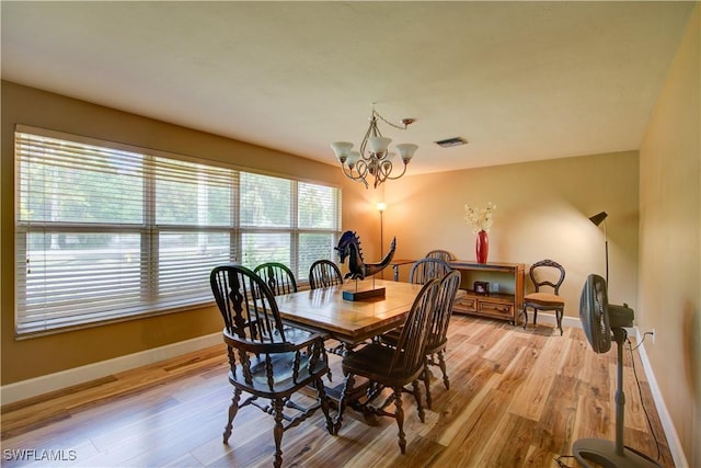 dining space with light wood finished floors, visible vents, baseboards, and an inviting chandelier