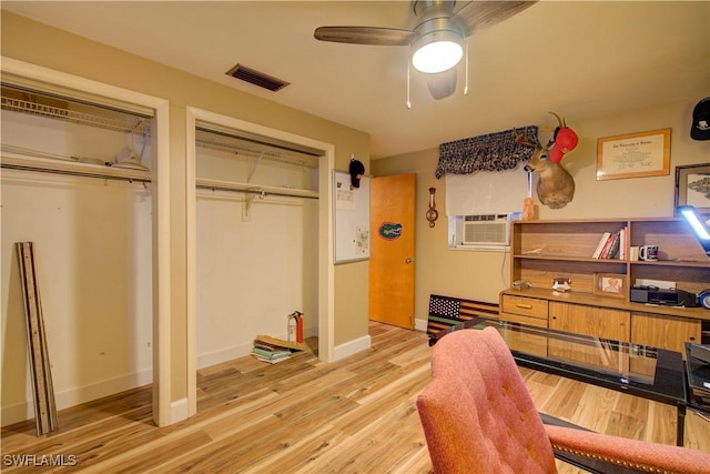 bedroom with visible vents, baseboards, a ceiling fan, light wood-style floors, and multiple closets