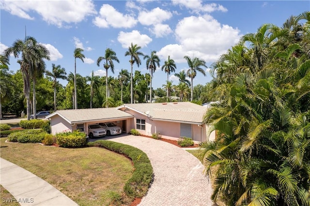 ranch-style house with a tiled roof, a front lawn, decorative driveway, and stucco siding
