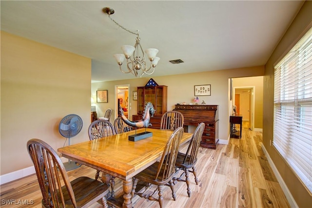 dining area featuring baseboards, light wood finished floors, a notable chandelier, and visible vents