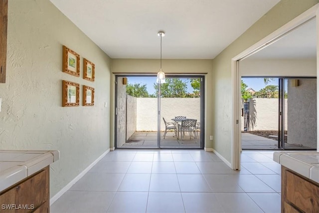 576 Retreat Dr Unit 101, Naples, FL 34110 - unfurnished dining area with a textured wall, light tile patterned floors, and baseboards