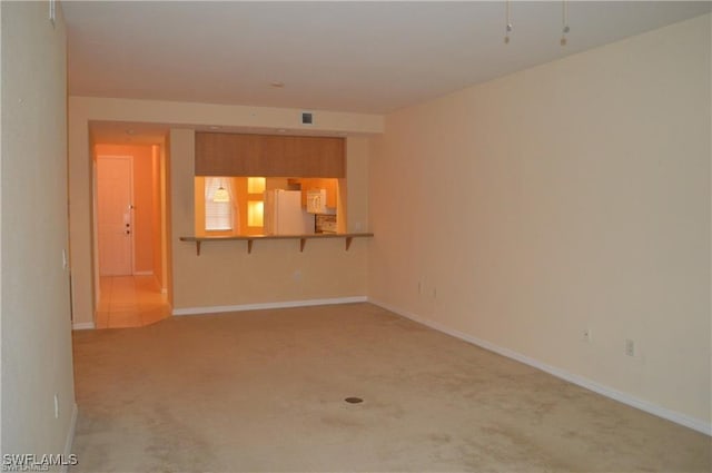 empty room featuring baseboards and light carpet