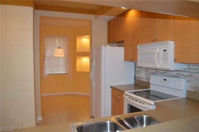 kitchen with baseboards, white appliances, light tile patterned floors, decorative backsplash, and a sink