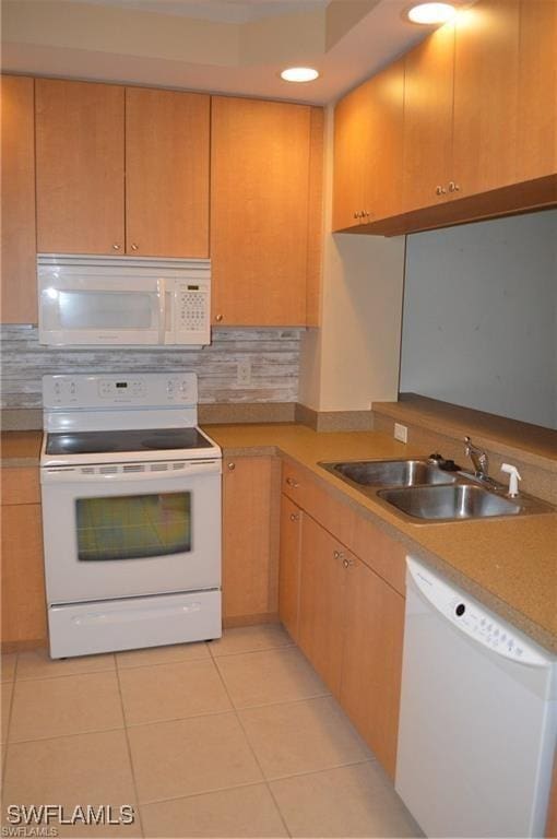 kitchen with light tile patterned floors, white appliances, light countertops, a sink, and decorative backsplash