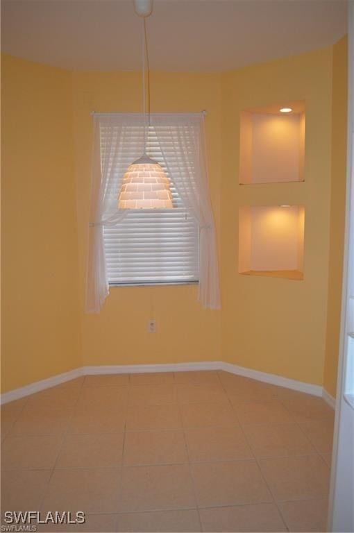 empty room featuring baseboards and light tile patterned flooring