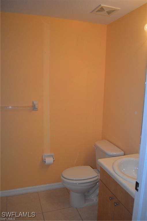 half bath featuring vanity, baseboards, tile patterned floors, toilet, and visible vents