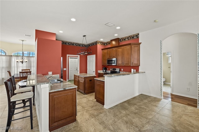 3428 SW 27th Pl, Cape Coral, FL 33914 - kitchen featuring a notable chandelier, a kitchen island with sink, stainless steel appliances, arched walkways, and a sink