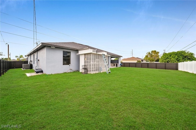 511 Tropicana Pkwy W, Cape Coral, FL 33993 - back of house featuring a yard, a fenced backyard, stucco siding, and central AC