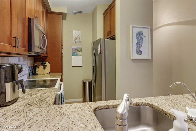 13199 Whitehaven Ln Unit 1808, Fort Myers, FL 33966 - kitchen featuring light stone counters, brown cabinetry, appliances with stainless steel finishes, a sink, and visible vents