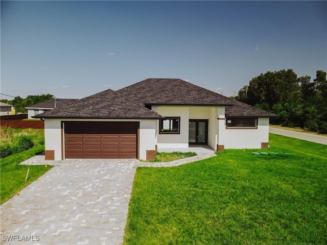 prairie-style house with a front yard, stucco siding, decorative driveway, and an attached garage