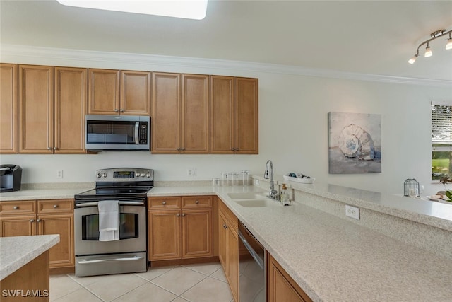 kitchen with light tile patterned floors, ornamental molding, appliances with stainless steel finishes, light countertops, and a sink