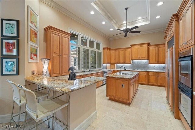 550 21st Ave S, Naples, FL 34102 - kitchen featuring a peninsula, brown cabinets, a sink, ceiling fan, and backsplash