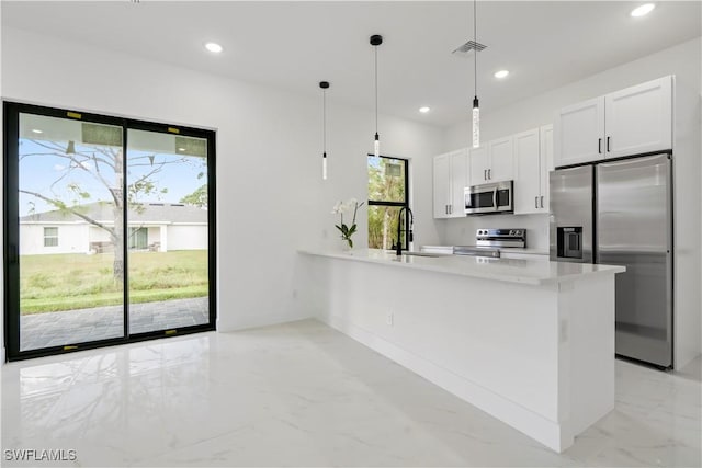 kitchen featuring appliances with stainless steel finishes, light countertops, white cabinets, a peninsula, and marble finish floor