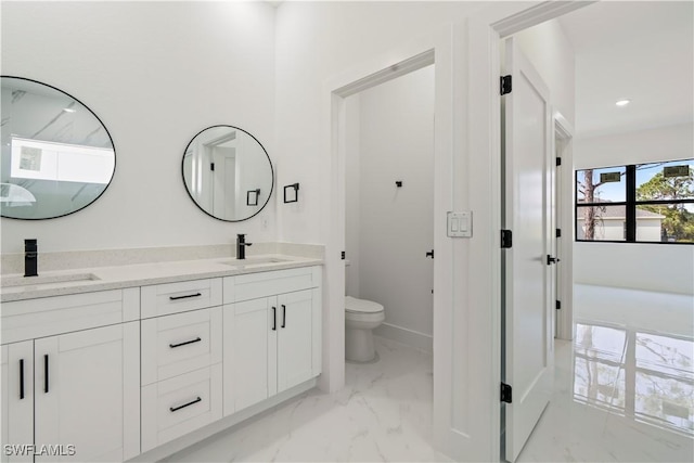 bathroom featuring double vanity, toilet, a sink, and marble finish floor