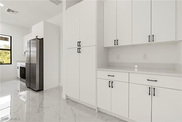 kitchen featuring visible vents, freestanding refrigerator, and marble finish floor