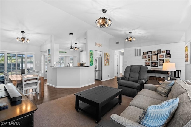 living area featuring visible vents, baseboards, a chandelier, vaulted ceiling, and dark wood-type flooring
