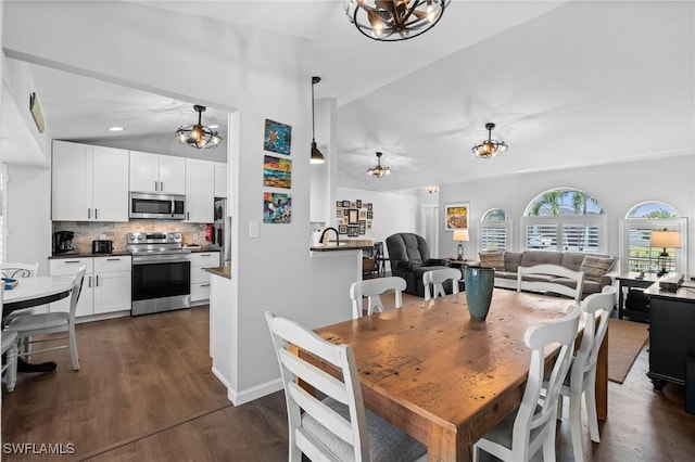 dining area featuring dark wood-style flooring, baseboards, an inviting chandelier, and lofted ceiling