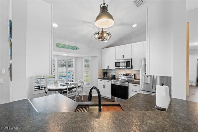kitchen with dark countertops, white cabinets, visible vents, decorative backsplash, and appliances with stainless steel finishes