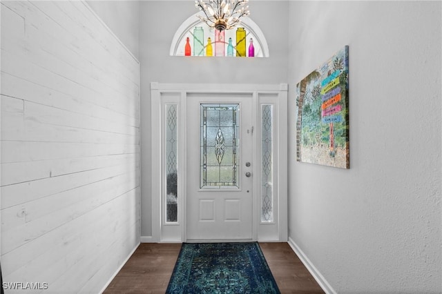 doorway to outside with baseboards, a chandelier, and dark wood finished floors