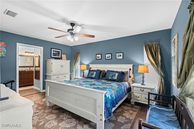 bedroom featuring visible vents, ensuite bathroom, a ceiling fan, and wood finished floors
