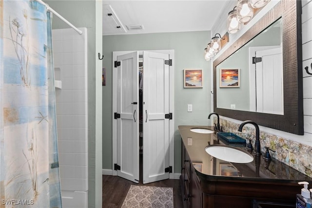 bathroom with a sink, double vanity, curtained shower, and wood finished floors