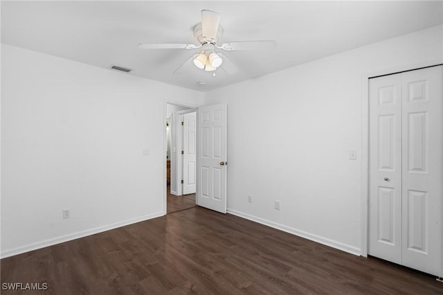 unfurnished bedroom with ceiling fan, dark wood finished floors, a closet, visible vents, and baseboards