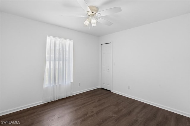 spare room with baseboards, a ceiling fan, and dark wood-style floors