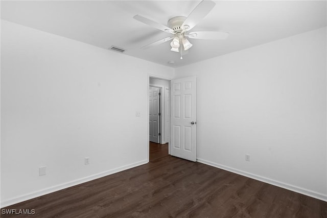 empty room with dark wood finished floors, baseboards, a ceiling fan, and visible vents