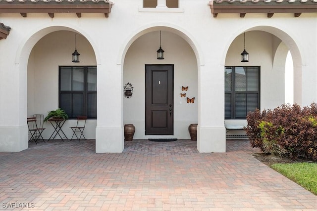 doorway to property featuring a porch, stucco siding, and a tile roof