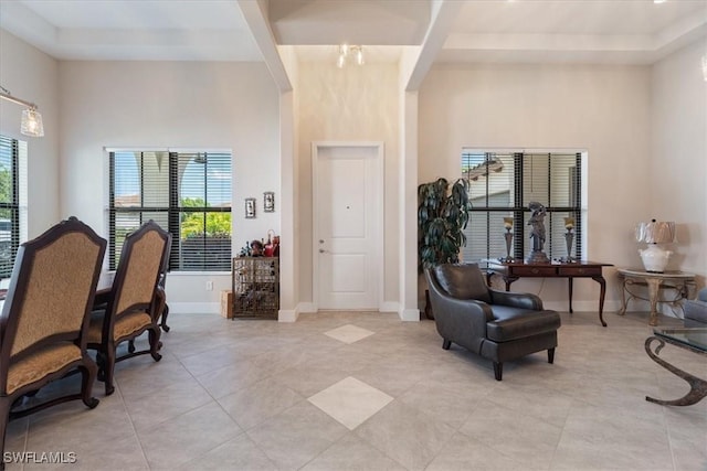 entryway featuring light tile patterned floors, baseboards, arched walkways, and a towering ceiling