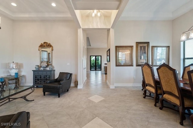 interior space with baseboards, recessed lighting, light tile patterned floors, a high ceiling, and a tray ceiling