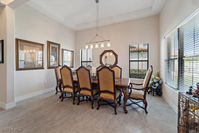 dining room with a tray ceiling, light tile patterned floors, and baseboards