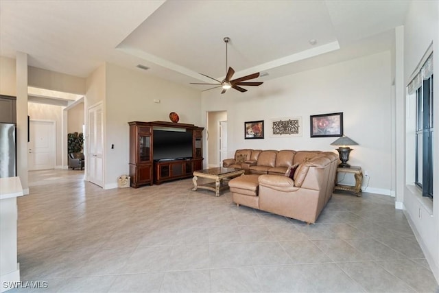 living area with baseboards, light tile patterned floors, a ceiling fan, visible vents, and a tray ceiling