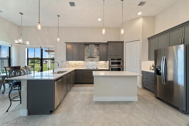 kitchen with a sink, wall chimney range hood, visible vents, and stainless steel appliances