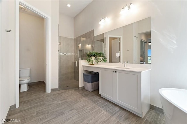 bathroom with a freestanding bath, toilet, vanity, wood finished floors, and a stall shower