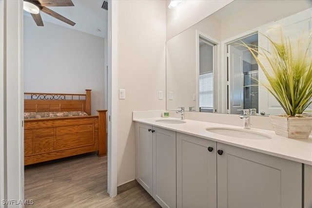 full bathroom with double vanity, ceiling fan, a sink, and wood finished floors